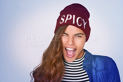 Buy stock photo Portrait, girl and rebel with silly expression in studio for fierce attitude, funky fashion and spicy beanie. Goofy, woman and wink with rock aesthetic, crazy gesture and style on purple background