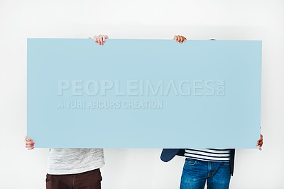 Buy stock photo Studio shot of two men covering themselves with a blank placard against a white background