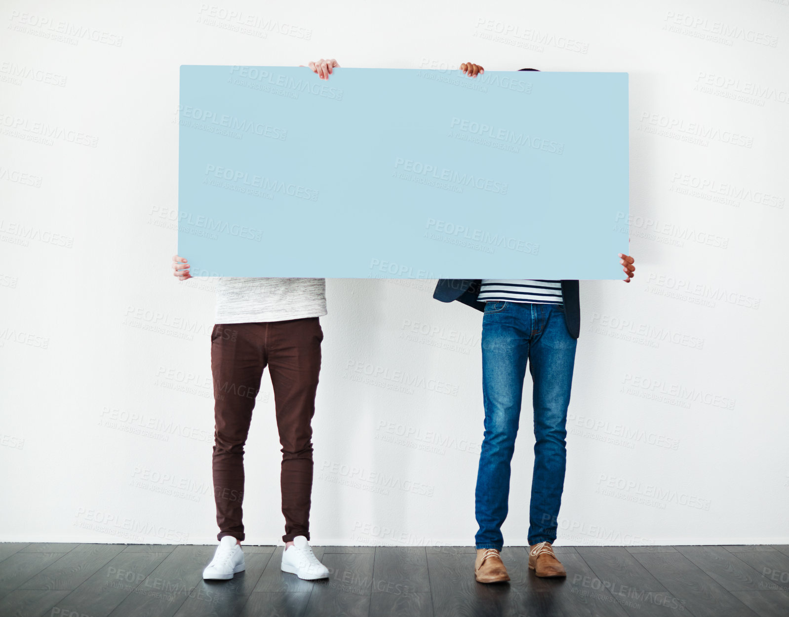 Buy stock photo Studio shot of two men covering themselves with a blank placard against a white background