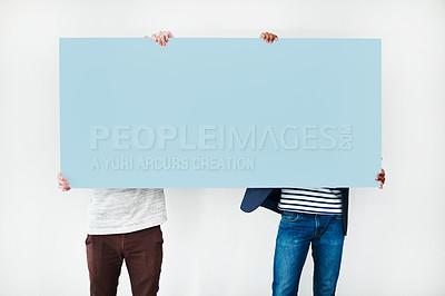 Buy stock photo Studio shot of two men covering themselves with a blank placard against a white background