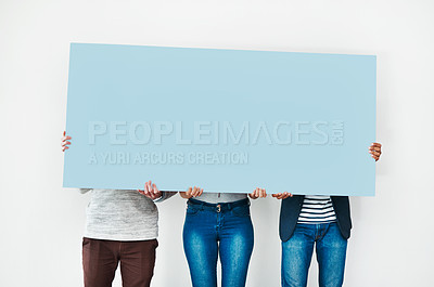 Buy stock photo Studio shot of a group of people covering themselves with a blank placard against a white background
