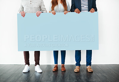 Buy stock photo Cropped studio shot of a group of people holding a blank placard against a white background