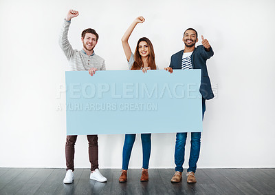 Buy stock photo Studio shot of a diverse group of young people holding a blank placard and cheering against a white background