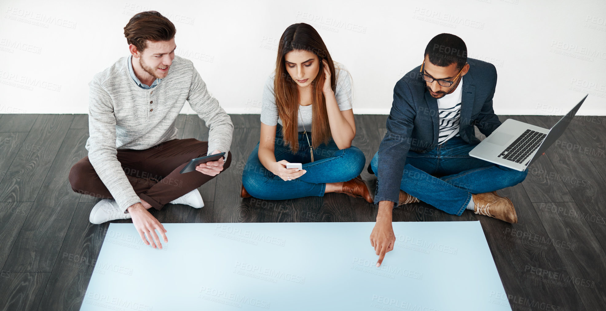 Buy stock photo Studio shot of a group of young people sitting on the floor and working on blank paper