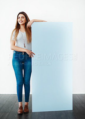Buy stock photo Studio shot of an attractive young women leaning against a blank placard against a white background