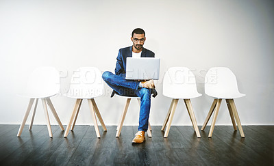 Buy stock photo Shot of a young businessman using a laptop while waiting in line