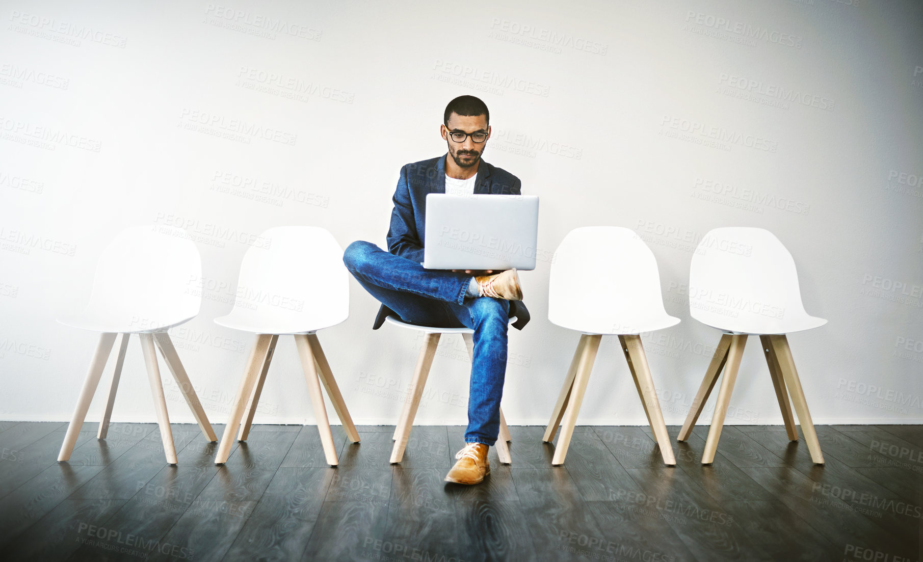 Buy stock photo Shot of a young businessman using a laptop while waiting in line