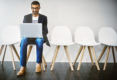 Buy stock photo Shot of a young businessman using a laptop while waiting in line