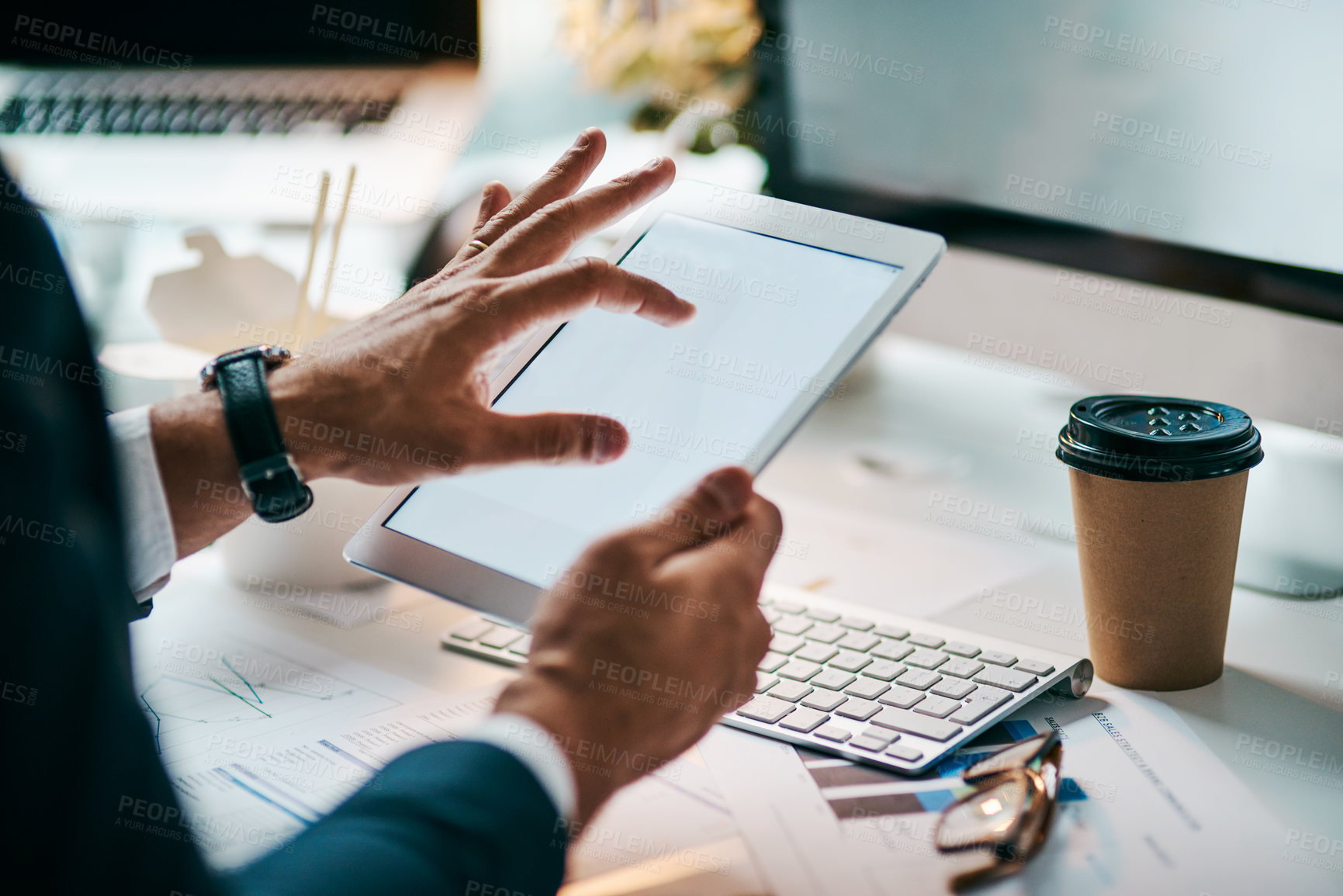 Buy stock photo Shot of an unrecognizable businessman browsing on his digital tablet while being seated in the office during the day