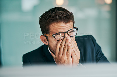 Buy stock photo Shot of a tired young businessman holding his eyes closed while being seated in the office
