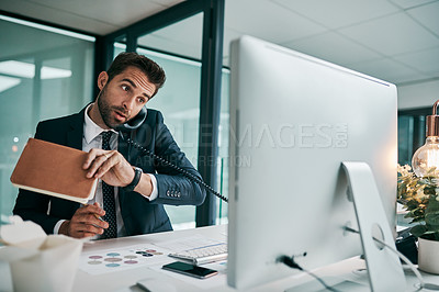 Buy stock photo Shot of a focused young businessman talking on the phone while holding a notebook in the office