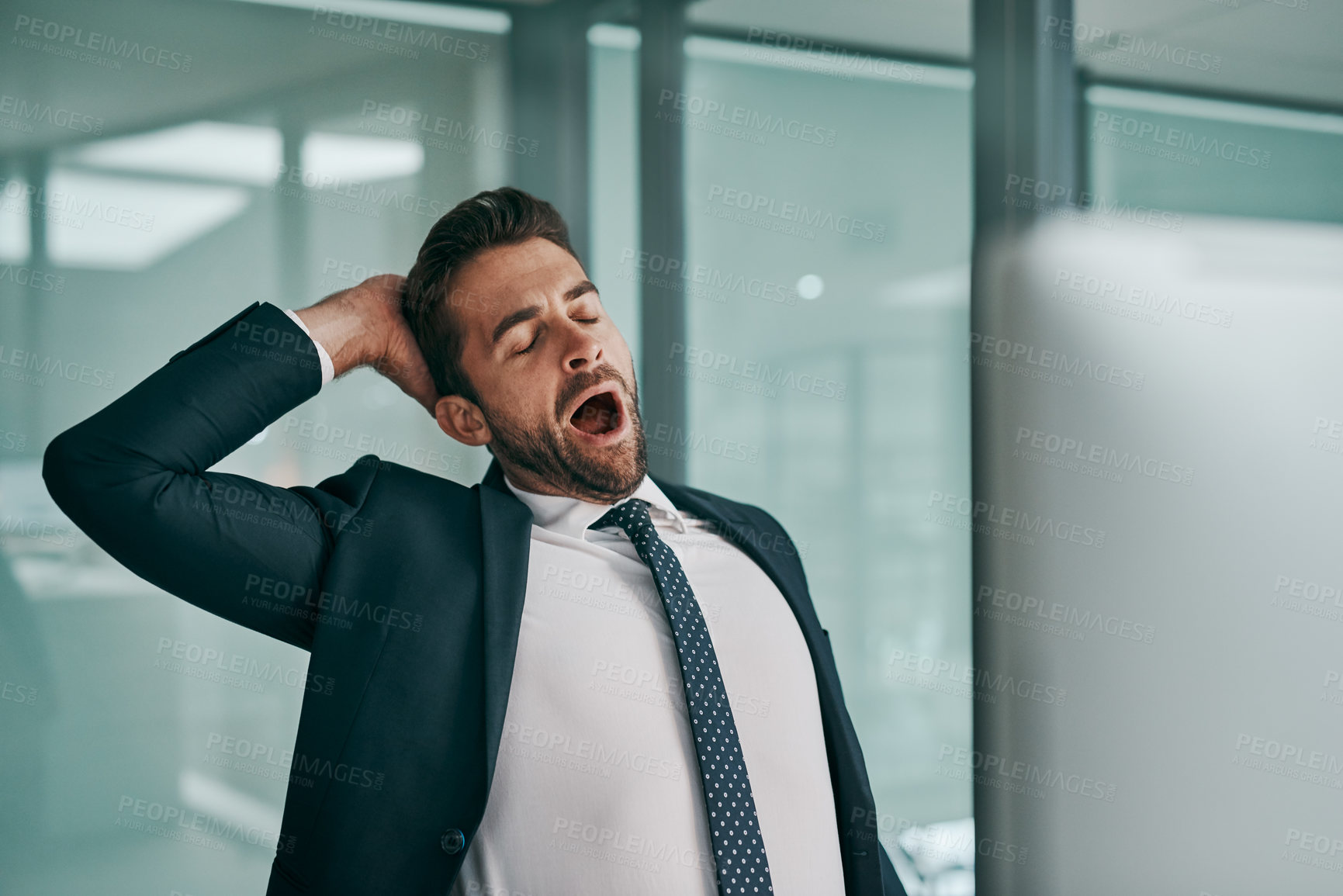 Buy stock photo Shot of a tired young businessman stretching while  yawning with his eyes closed inside of the office