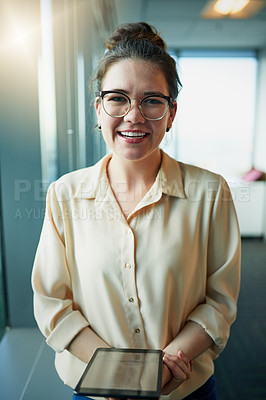 Buy stock photo Portrait of a cheerful young businesswoman holding a digital tablet while standing in the office during the day