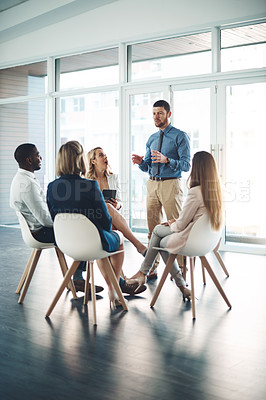 Buy stock photo Full length shot of a young businessman addressing his colleagues during a meeting in the office