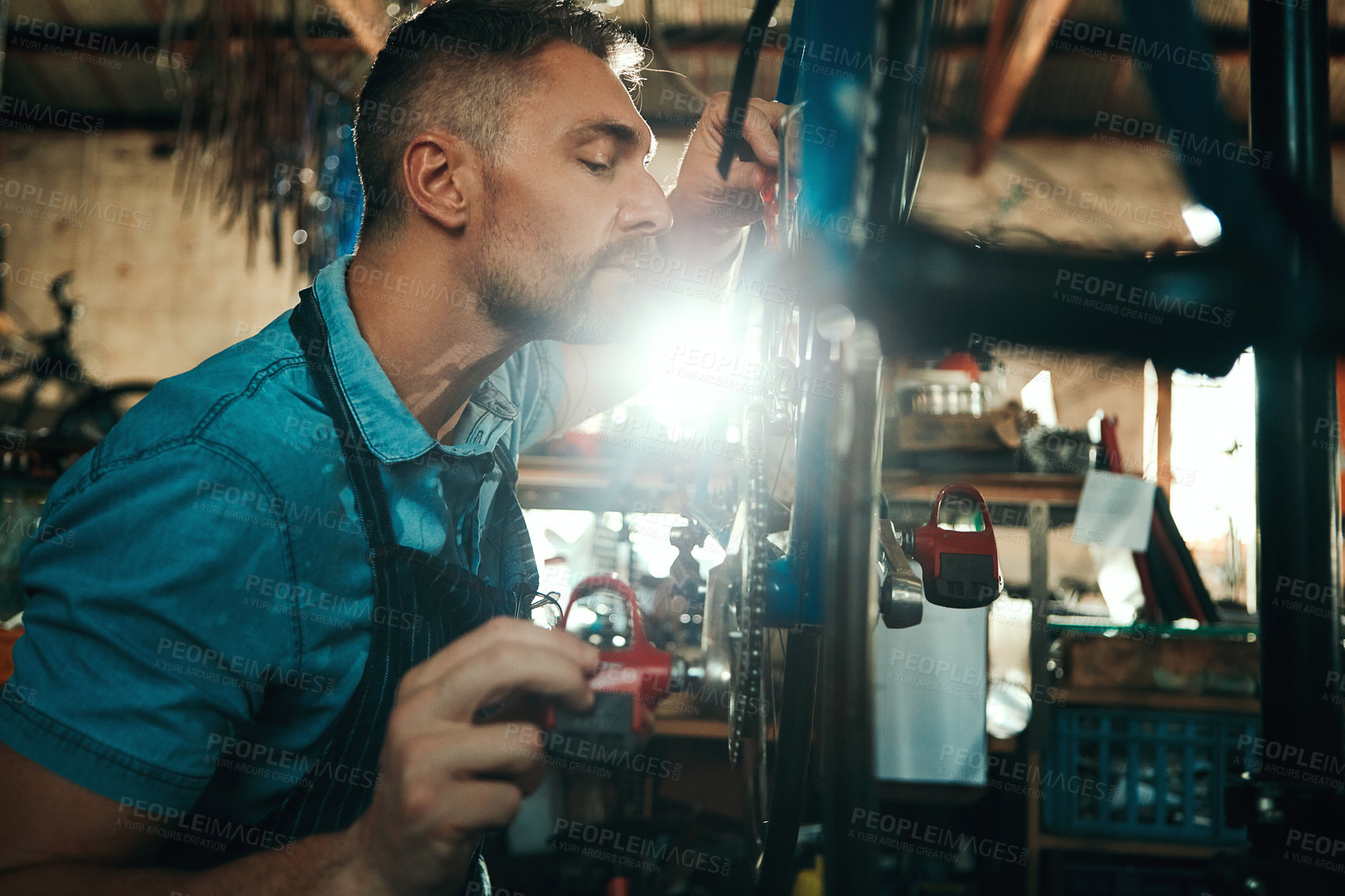 Buy stock photo Bicycle technician, working and repair in shop with frame, chain and tools for maintenance or cycling. Man, bike and mechanic in workshop as handyman for gear, inspection and safety with experience