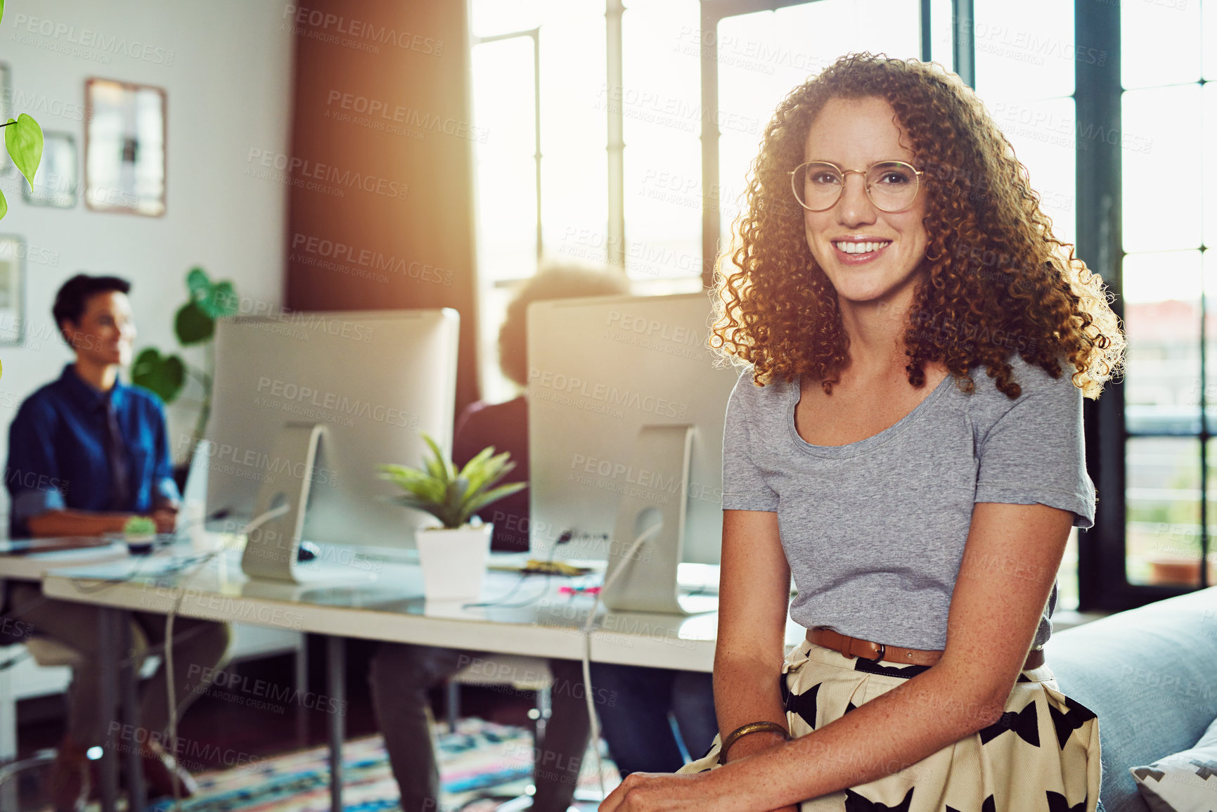 Buy stock photo Portrait of a young designer sitting in an office with her colleagues in the background