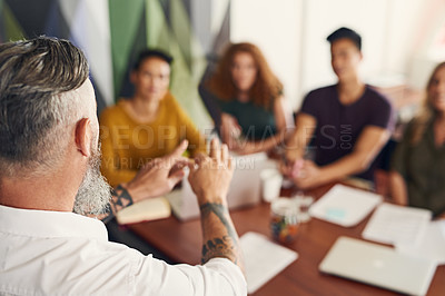 Buy stock photo Rearview shot of a mature businessman giving a presentation to his colleagues in an office