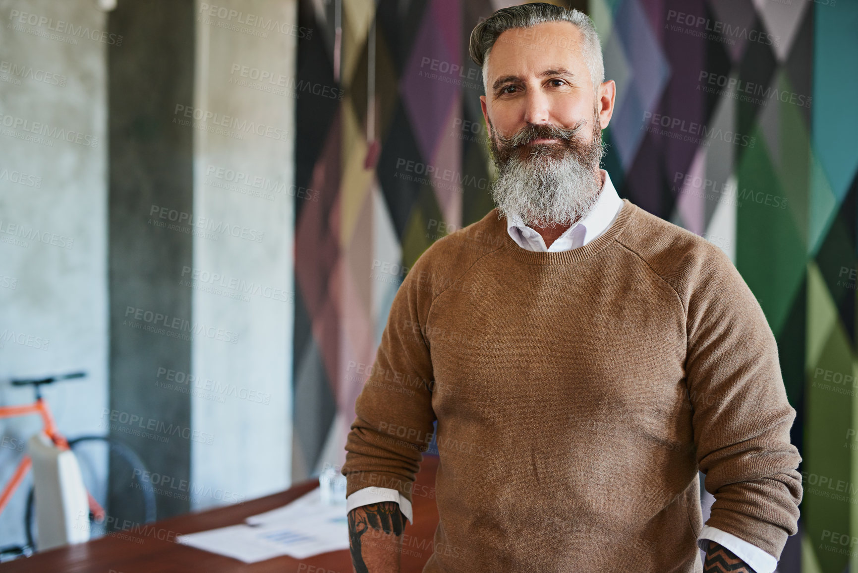 Buy stock photo Portrait of a cheerful middle aged man looking at the camera while standing alone in his office during the day