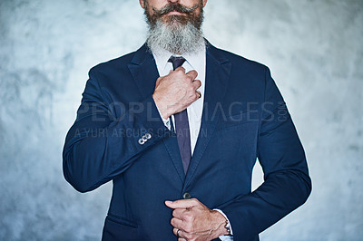 Buy stock photo Studio shot of a handsome middle aged businessman wearing a formal suit while standing against a grey background