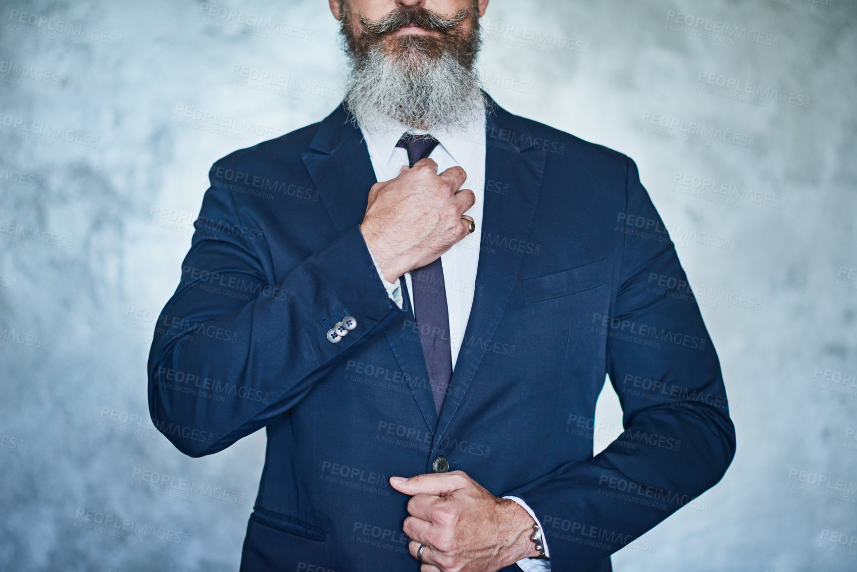 Buy stock photo Studio shot of a handsome middle aged businessman wearing a formal suit while standing against a grey background