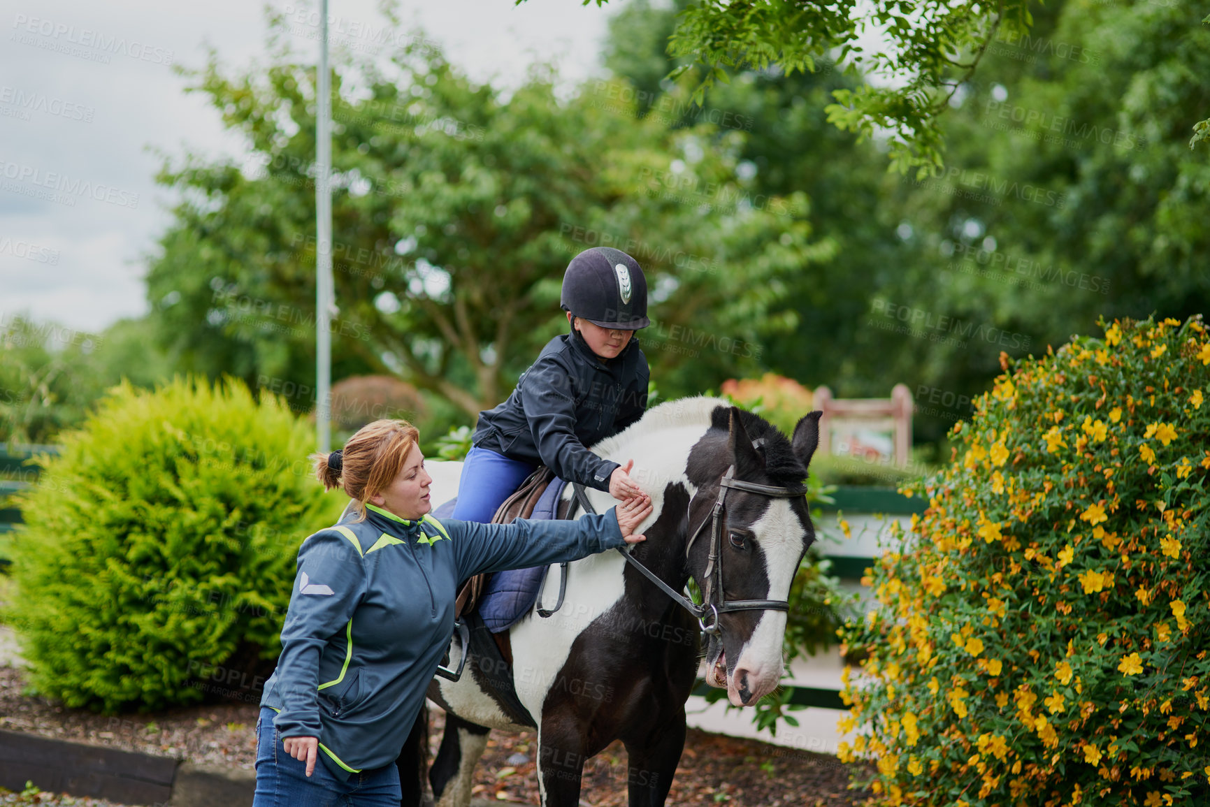 Buy stock photo Shot of a horse riding trainer teaching a young girl how to ride a horse outdoors