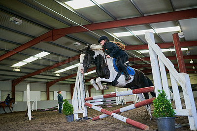 Buy stock photo Shot of a young girl horse riding indoors