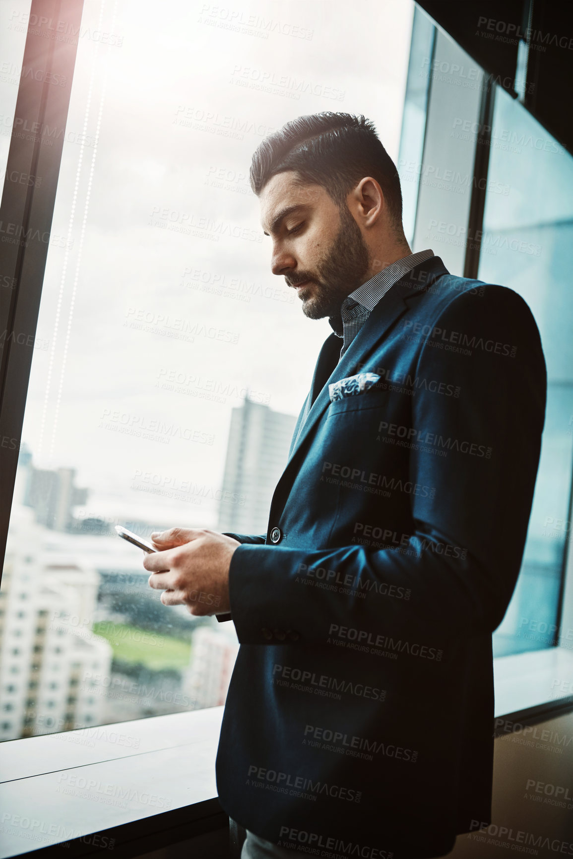 Buy stock photo Business, window and Indian man in office for phone, search or social media, newsletter or client communication. Smartphone, technology and entrepreneur with app for email, chat or text notification