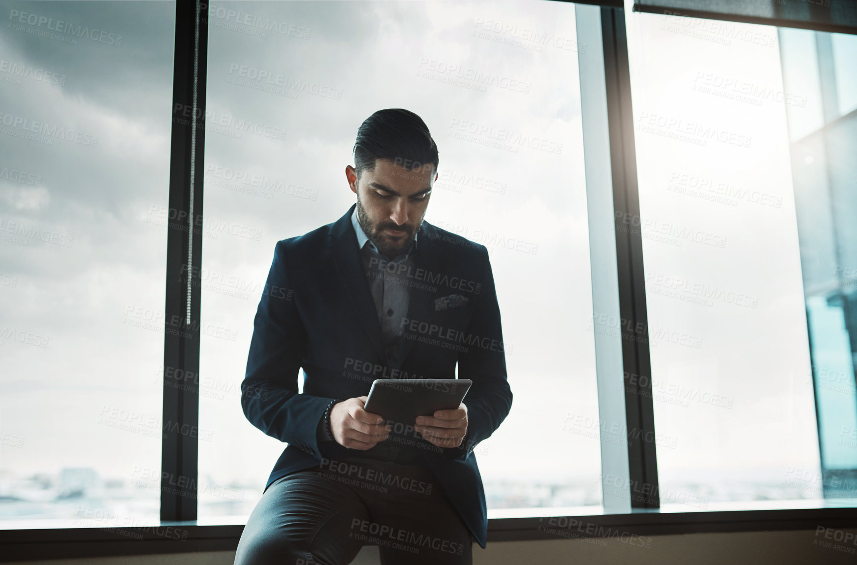 Buy stock photo Shot of a young businessman using a digital tablet in a modern office