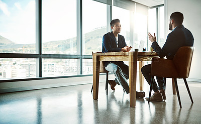 Buy stock photo Shot of two young businessmen having a discussion at a desk in a modern office