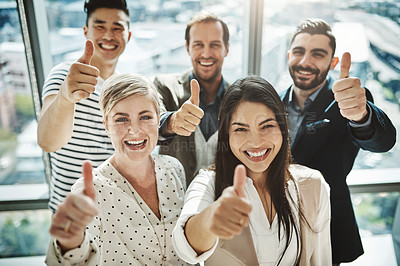 Buy stock photo Portrait of a group of cheerful businesspeople standing together while showing thumbs up to the camera inside of the office
