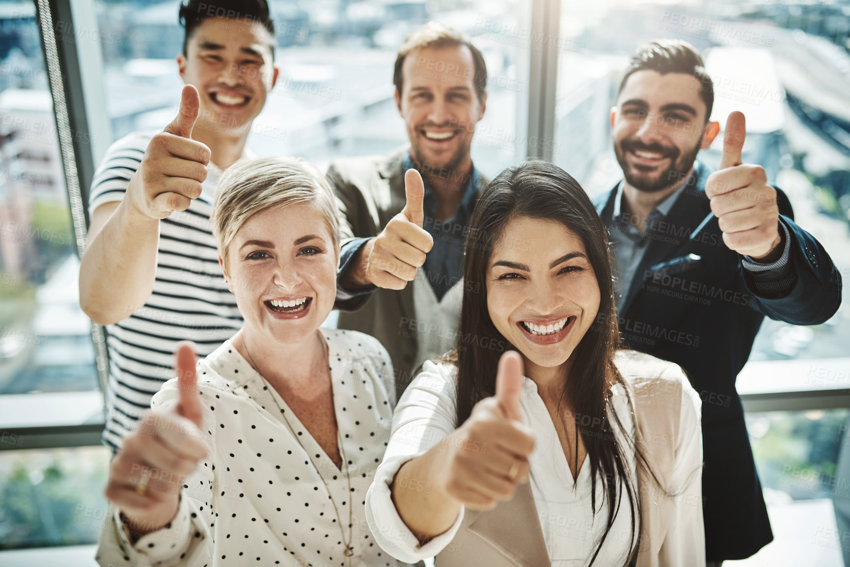 Buy stock photo Portrait of a group of cheerful businesspeople standing together while showing thumbs up to the camera inside of the office