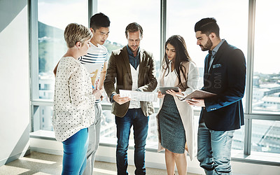 Buy stock photo Shot of a group of focused business people working together on ideas while standing in the office during the day