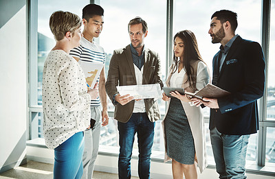 Buy stock photo Shot of a group of focused business people working together on ideas while standing in the office during the day