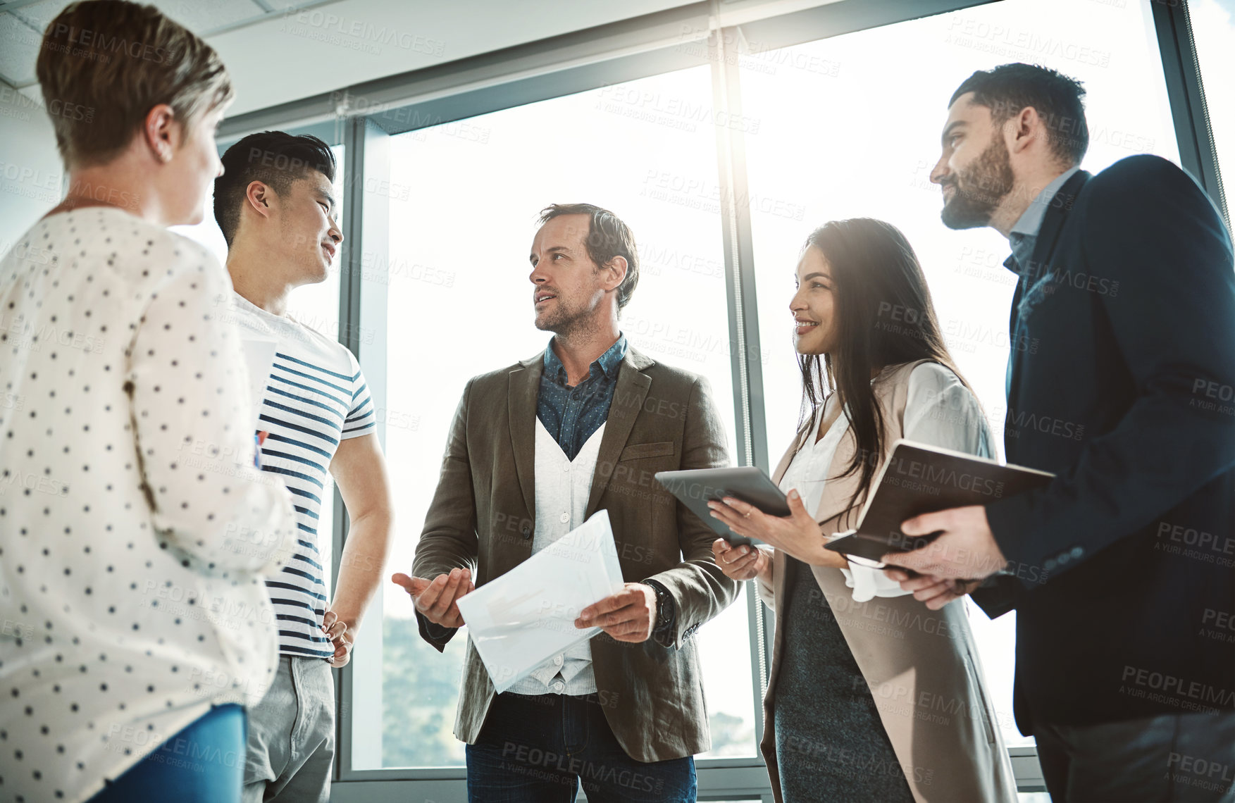 Buy stock photo Shot of a group of focused business people working together on ideas while standing in the office during the day