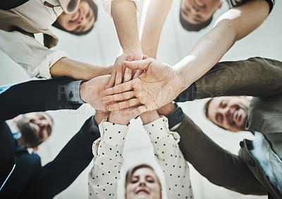 Buy stock photo Low angle shot of a group of cheerful businesspeople forming a huddle with their hands and looking down inside of the office