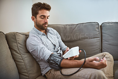 Buy stock photo Hypertension, machine and man exam blood pressure in a home sofa or living room for medical or health test. Monitor, reading and person with equipment for chronic disease due to stress