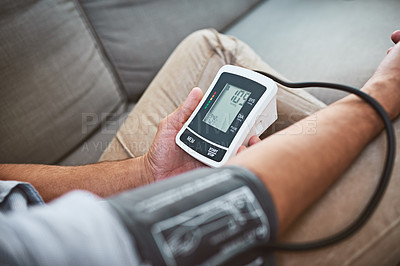 Buy stock photo Hypertension, machine and person test blood pressure in a home sofa or living room for medical or health exam. Monitor, reading and man with closeup of equipment for chronic disease due to stress