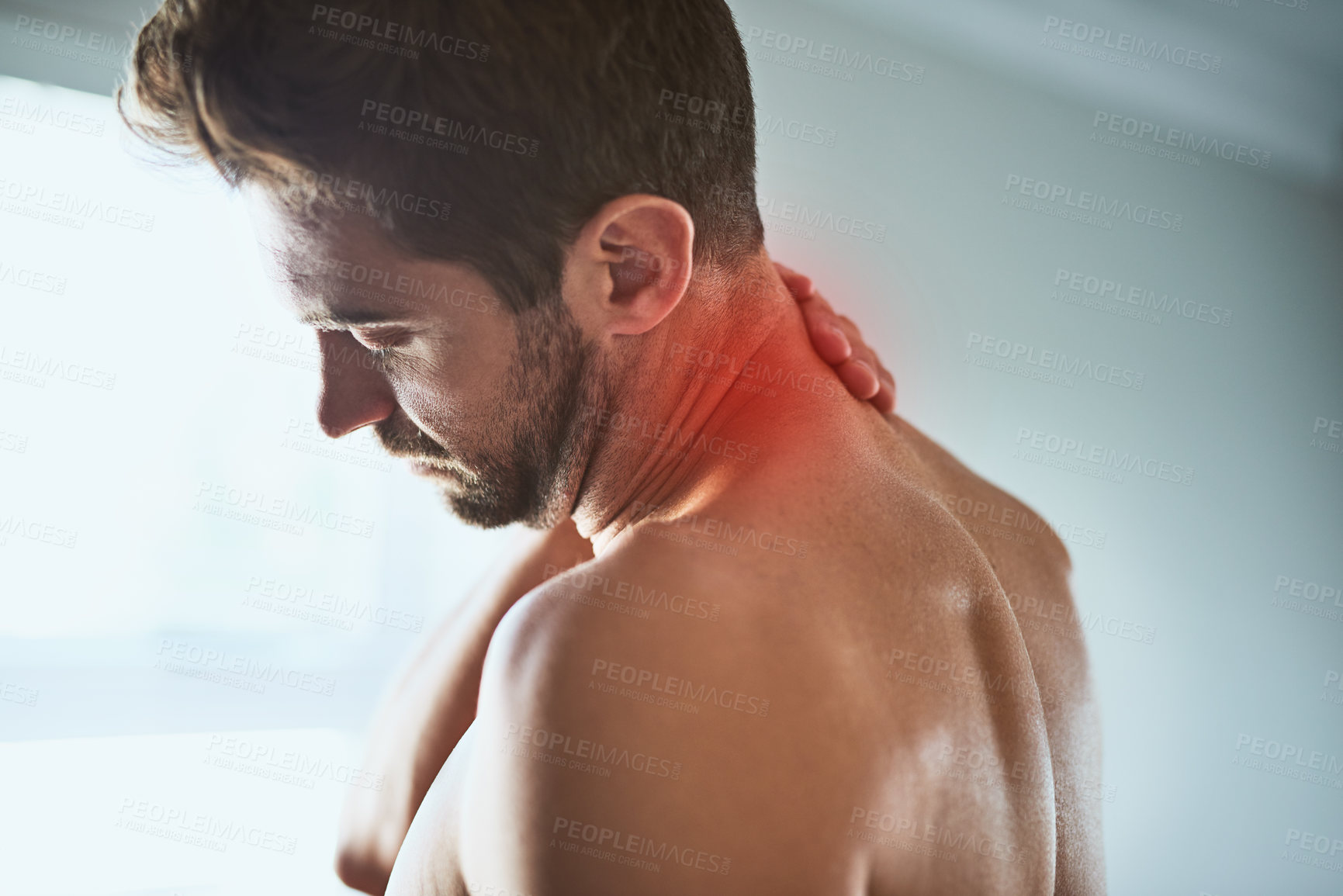 Buy stock photo Shot of a shirtless unrecognizable man holding his neck in discomfort due to pain inside at home