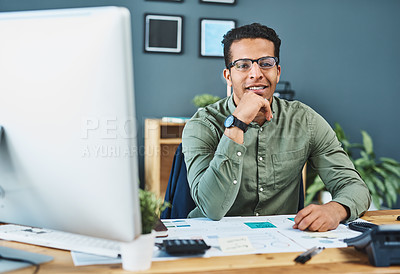 Buy stock photo Portrait of a cheerful young businessman seated behind his desk busy working inside of the office during the day