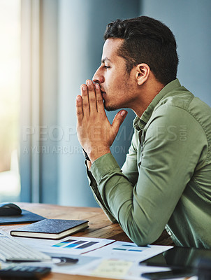 Buy stock photo Shot of a focused young businessman seated behind his desk and contemplating inside of the office during the day