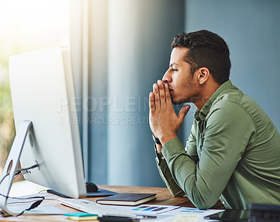 Buy stock photo Shot of a focused young businessman seated behind his desk and contemplating inside of the office during the day