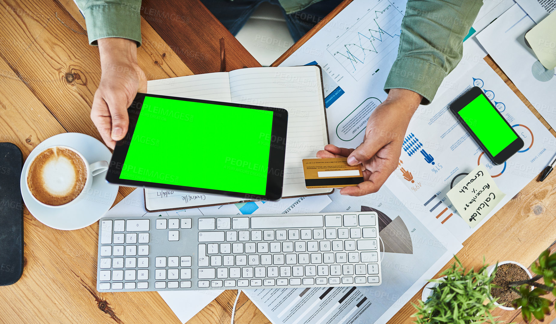 Buy stock photo High angle shot of an unrecognizable businessman holding a digital tablet and credit card while working behind his desk inside of the office