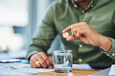 Buy stock photo Shot of an unrecognizable person putting a dissolvable tablet in a glass of water while being seated at a desk in the office