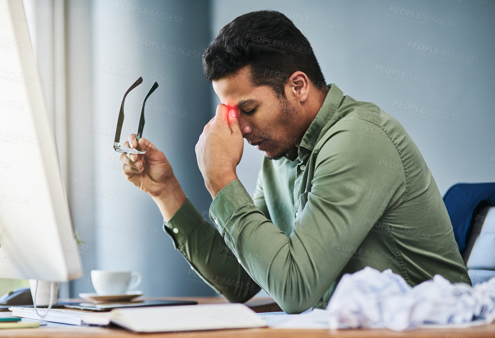 Buy stock photo Shot of a uncomfortable young businessman holding his forehead with his hand in pain while being seated at his desk at the office