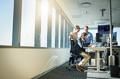 Buy stock photo Shot of a group of young businesspeople working together on a computer inside of the office during the day