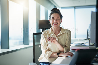Buy stock photo Portrait of a cheerful young businesswoman holding a pair of glasses while being seated at her desk at the office