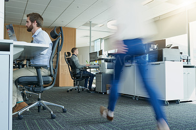Buy stock photo Low angle shot of a group of businesspeople working in the office while a unrecognizable woman walks pass
