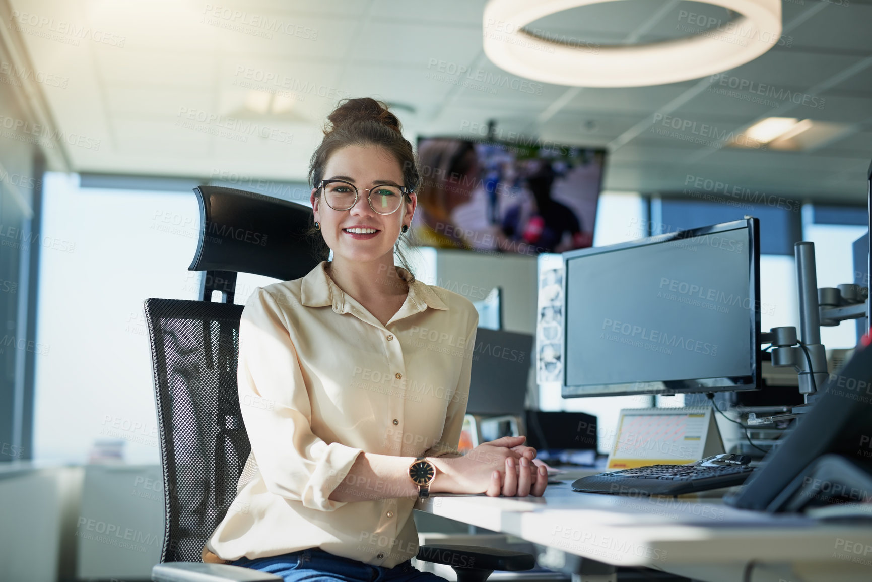 Buy stock photo Portrait of a cheerful young businesswoman seated at her desk inside of the office during the day