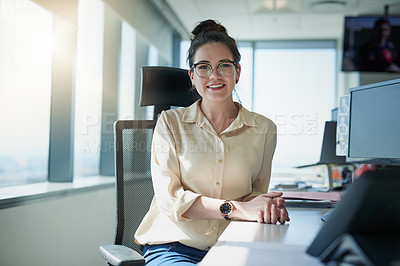 Buy stock photo Portrait of a cheerful young businesswoman seated at her desk inside of the office during the day