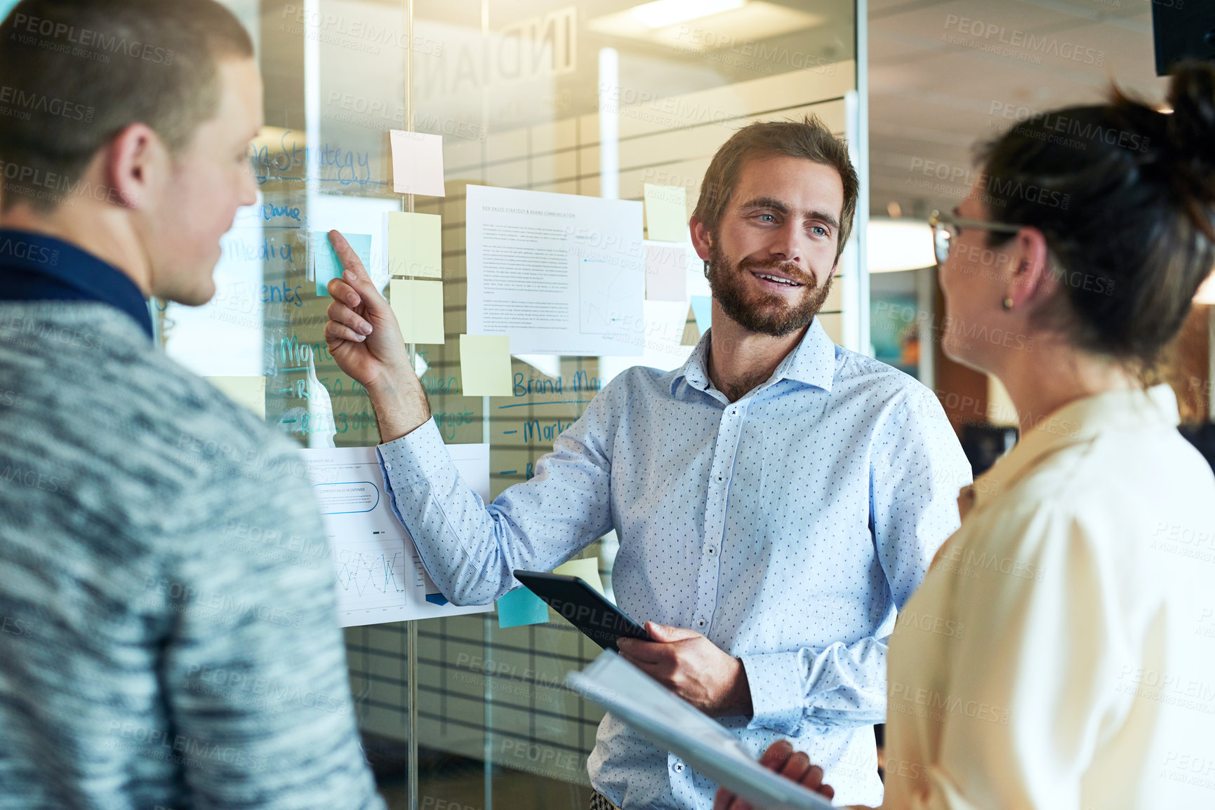 Buy stock photo Shot of a group of businesspeople brainstorming with notes on a glass wall in an office